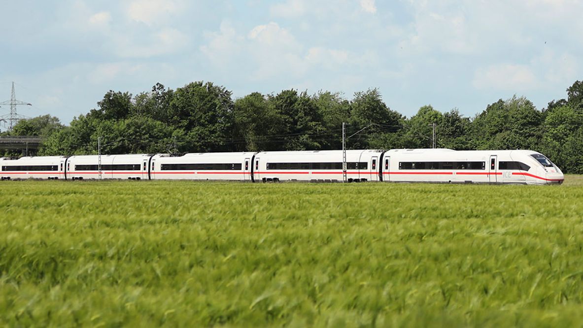 Ein ICE fährt durch eine grüne Landschaft