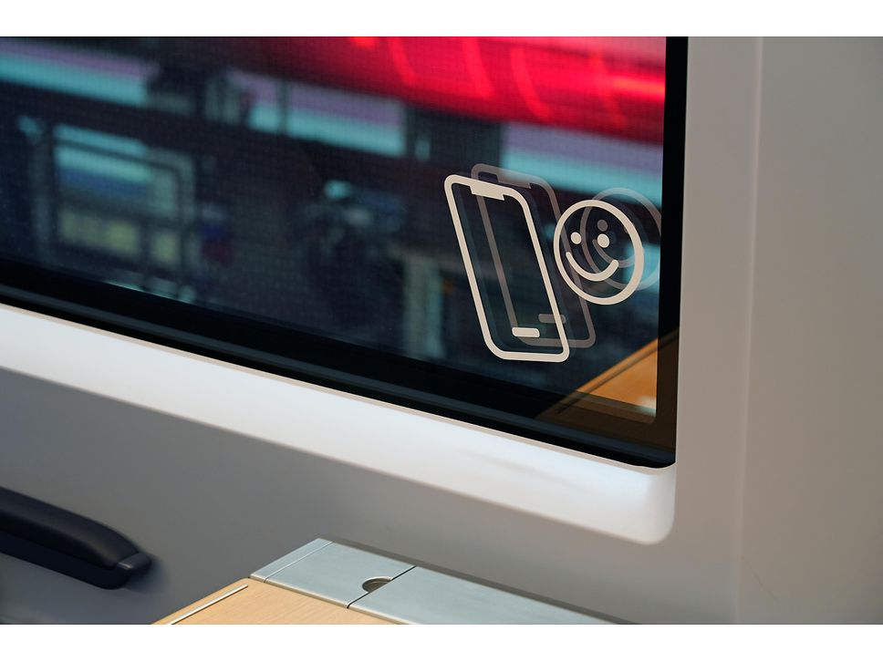 Unten rechts in einem ICE-Fenster ist ein kleines Bildchen mit einem lächelnden Smiley und einem Handy angebracht.