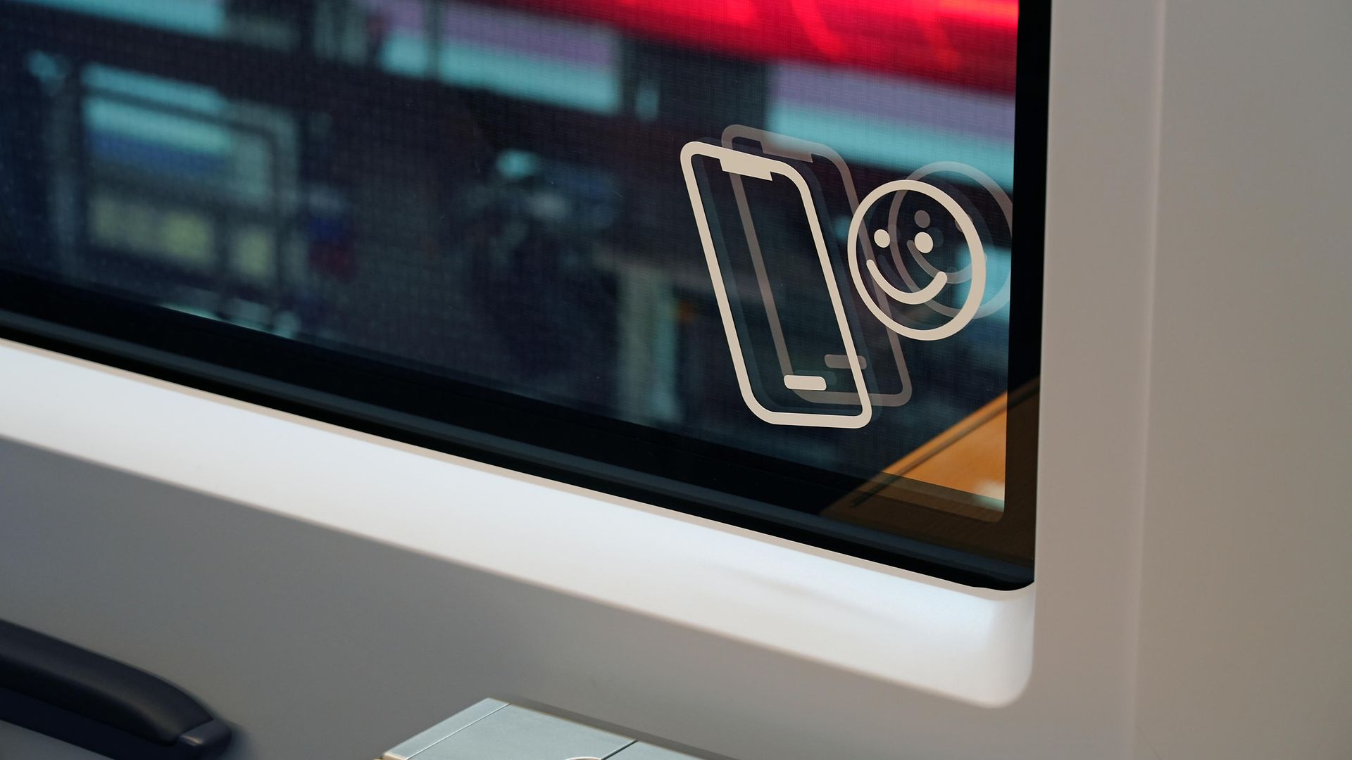 Unten rechts in einem ICE-Fenster ist ein kleines Bildchen mit einem lächelnden Smiley und einem Handy angebracht.